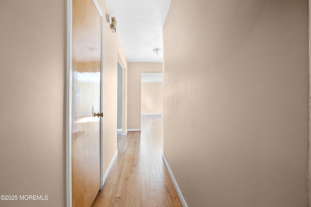 corridor featuring baseboards and light wood-style floors