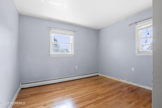 unfurnished room with baseboard heating, baseboards, and wood finished floors