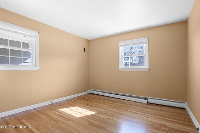 empty room featuring wood finished floors, baseboards, and a baseboard radiator