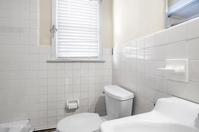 bathroom with toilet, tile walls, and wainscoting