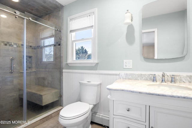 bathroom with vanity, a wainscoted wall, a baseboard radiator, a shower stall, and toilet