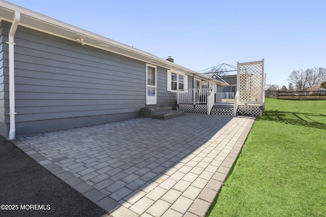 rear view of house with a patio, a yard, fence, and a wooden deck