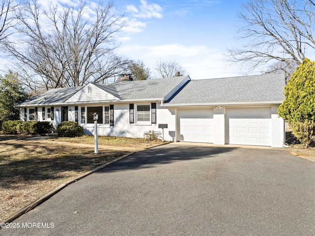 ranch-style house featuring stucco siding, aphalt driveway, roof with shingles, a garage, and a chimney