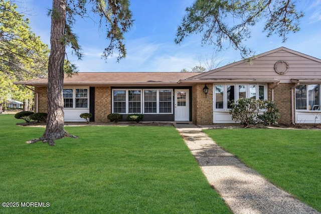 ranch-style home featuring a front lawn and brick siding