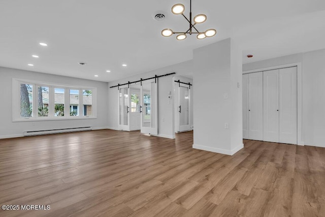 unfurnished living room with light wood-type flooring, a baseboard radiator, a barn door, and visible vents