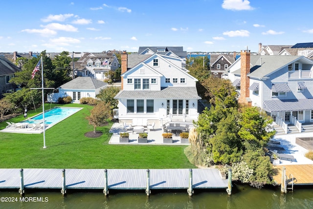 back of house featuring a patio area, a lawn, a residential view, and a water view