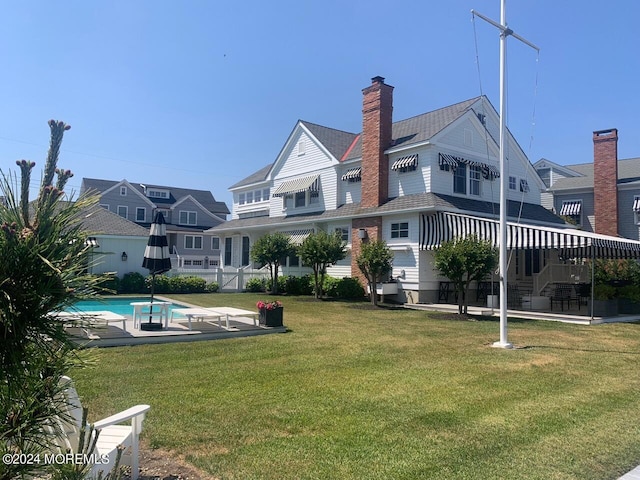 back of house featuring a fenced in pool, a yard, a chimney, and a patio area