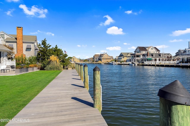 view of dock with a residential view, a lawn, and a water view