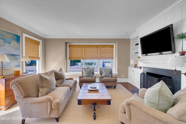 living area with ornamental molding, a tiled fireplace, built in features, wood finished floors, and baseboards