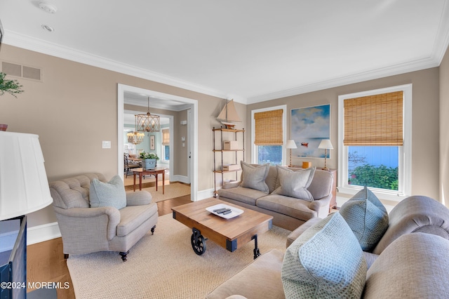 living area with crown molding, a notable chandelier, wood finished floors, and baseboards