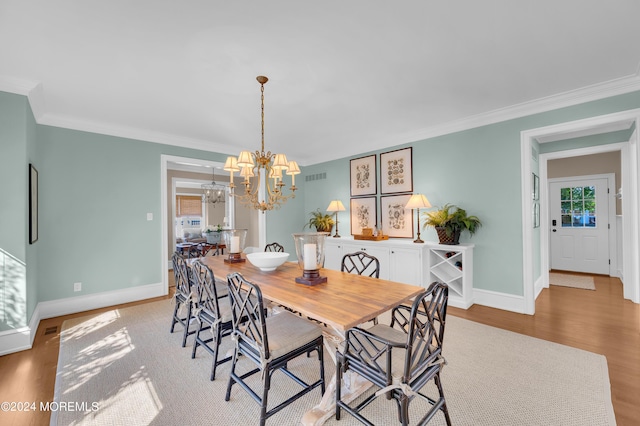 dining room with wood finished floors, baseboards, visible vents, crown molding, and a chandelier