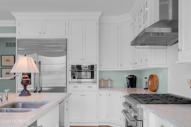 kitchen with high end appliances, visible vents, a sink, white cabinetry, and wall chimney exhaust hood