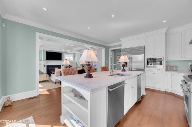 kitchen featuring high end appliances, visible vents, a fireplace, a sink, and crown molding