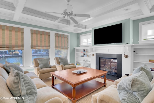 living area featuring a glass covered fireplace, beamed ceiling, coffered ceiling, and a ceiling fan