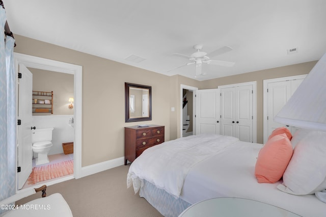 bedroom with visible vents, baseboards, multiple closets, light colored carpet, and ensuite bathroom