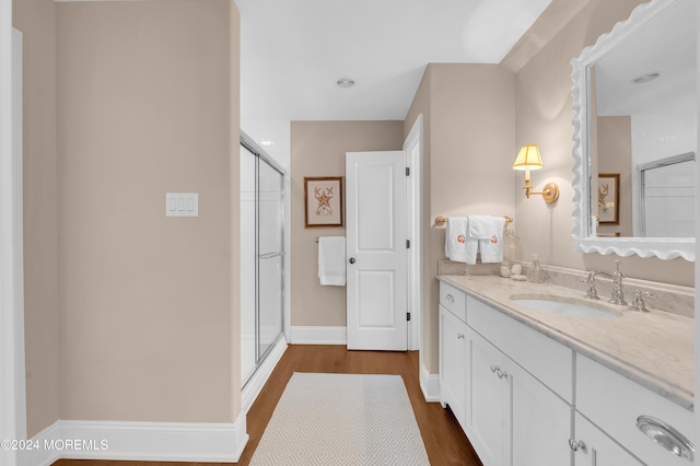 full bathroom with vanity, an enclosed shower, wood finished floors, and baseboards