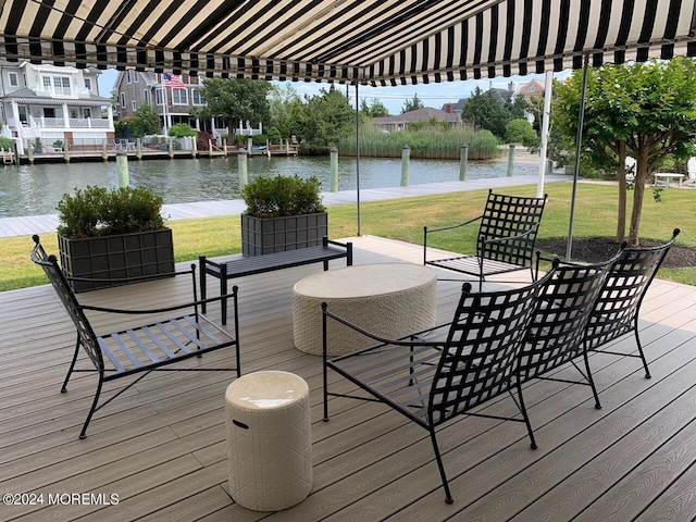 deck with outdoor dining space, a lawn, and a water view