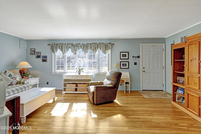 living room with crown molding, baseboards, and light wood-type flooring