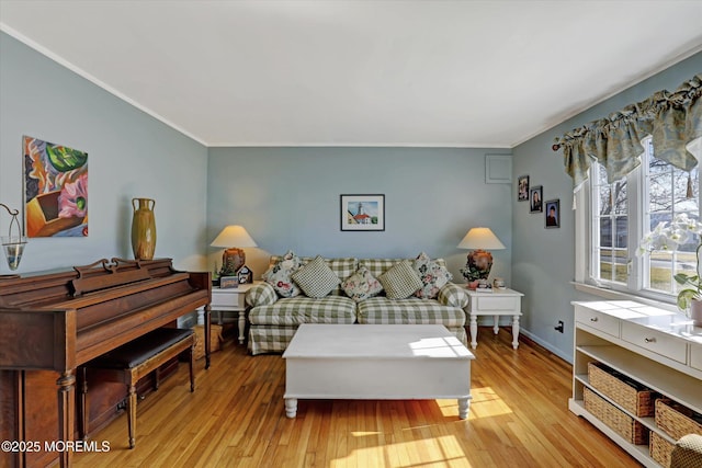 living area featuring light wood-style floors, baseboards, and ornamental molding