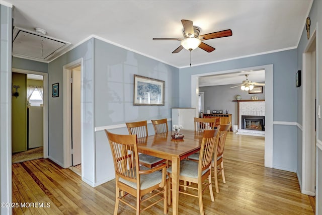 dining area featuring attic access, crown molding, and light wood finished floors