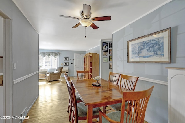 dining area with light wood-type flooring, baseboards, and a ceiling fan