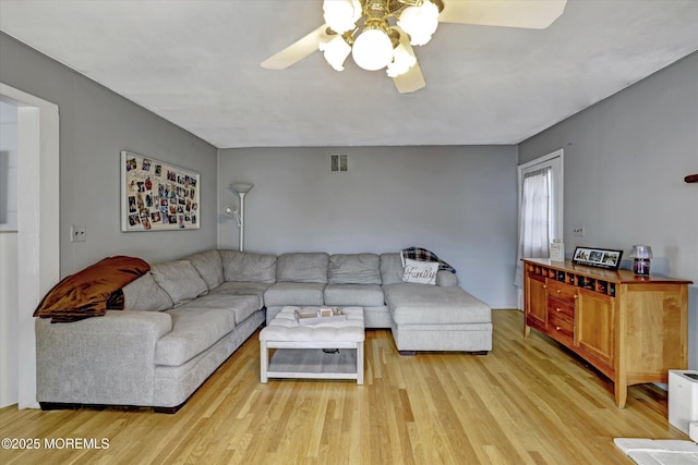 living room featuring visible vents, light wood-style flooring, and ceiling fan