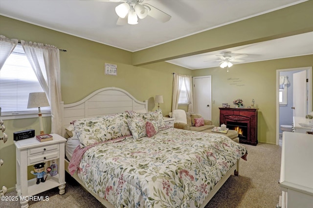 carpeted bedroom with a warm lit fireplace and ceiling fan