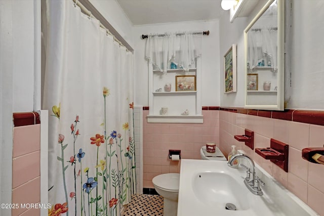 full bathroom with a sink, curtained shower, toilet, and tile walls