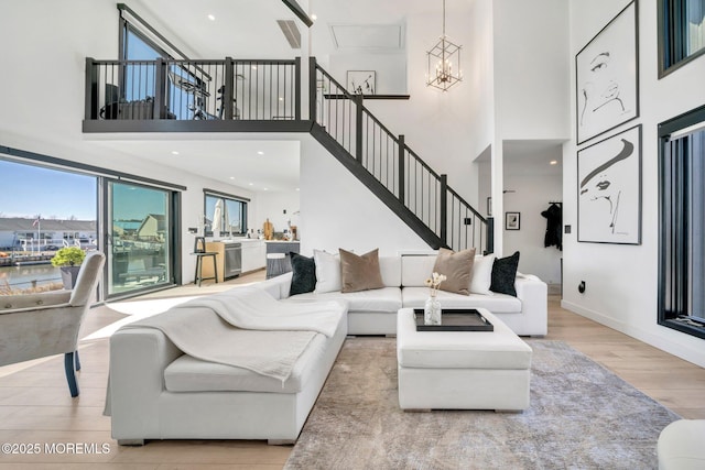 living area with baseboards, stairs, a high ceiling, an inviting chandelier, and wood finished floors