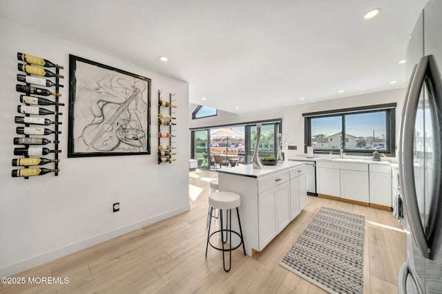 kitchen featuring a kitchen island, appliances with stainless steel finishes, light wood-style flooring, and white cabinetry