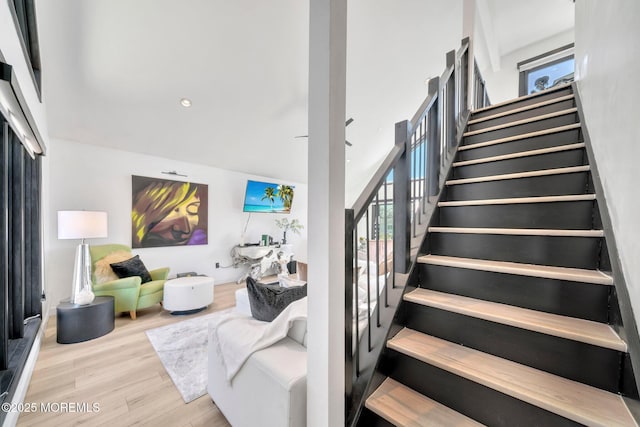 stairs with wood finished floors and a towering ceiling