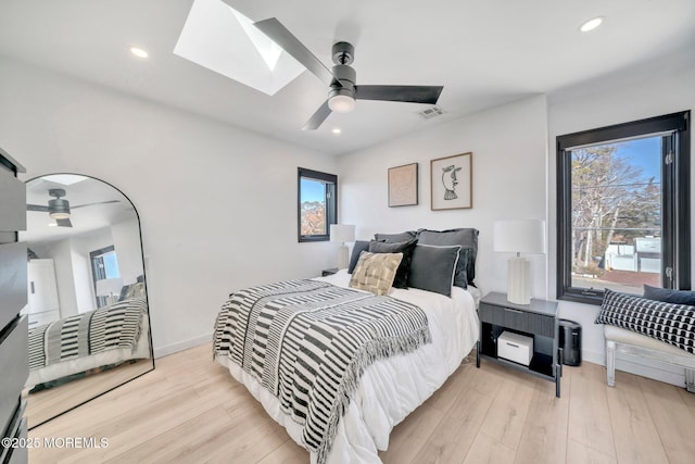 bedroom featuring visible vents, a skylight, baseboards, and wood finished floors