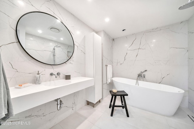 full bathroom featuring a soaking tub, stone wall, and a sink