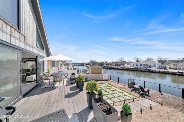 deck with outdoor dining area, a water view, and a residential view