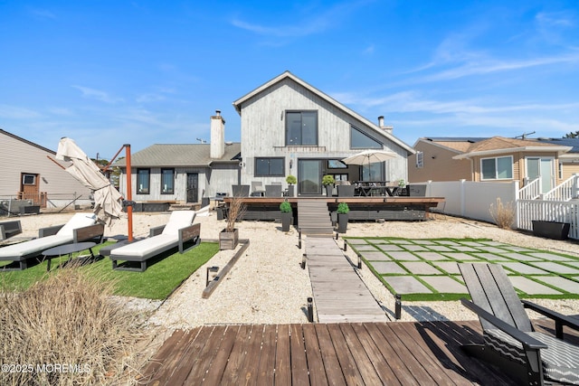 rear view of house with a patio, a wooden deck, fence, and a chimney