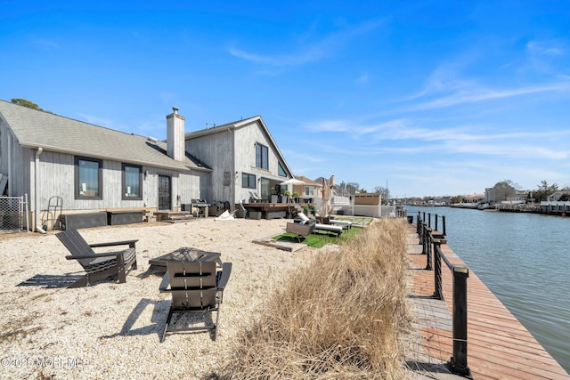 exterior space featuring a fire pit, a dock, and a water view