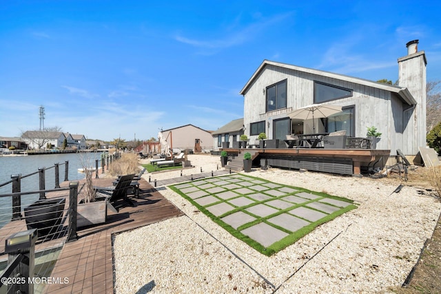 view of yard with a deck with water view, a patio, and a boat dock