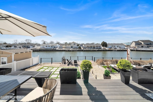 deck featuring a residential view, fence, and a water view