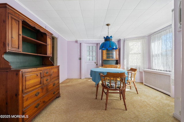 dining area featuring baseboards, light colored carpet, and radiator heating unit