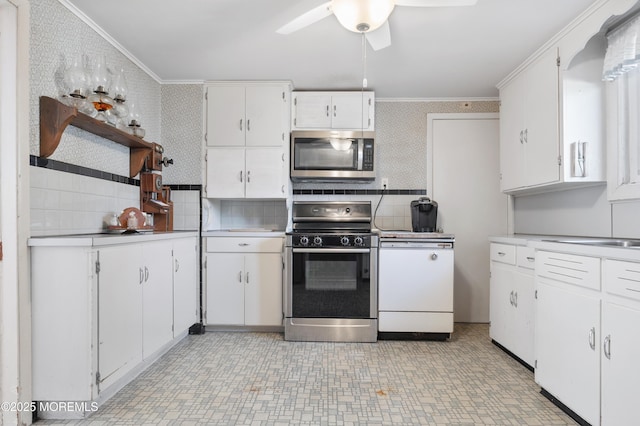 kitchen featuring wallpapered walls, stainless steel microwave, crown molding, and gas stove