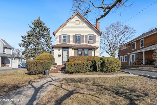 traditional-style home featuring a front yard and a chimney