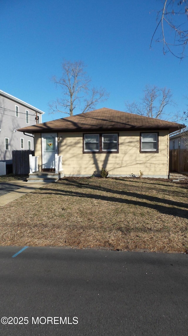 view of front of home with a front yard and fence