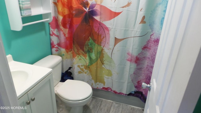 bathroom featuring curtained shower, toilet, wood finished floors, and vanity