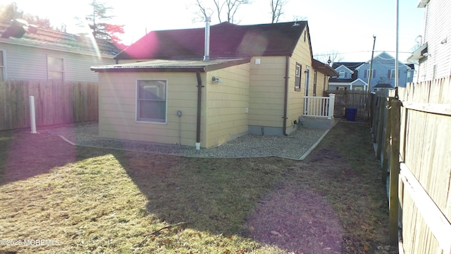 rear view of house featuring a lawn and a fenced backyard