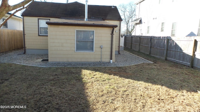 rear view of property with a yard, fence, and roof with shingles