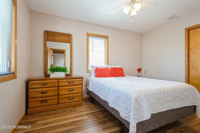 bedroom with visible vents, multiple windows, baseboards, and wood finished floors