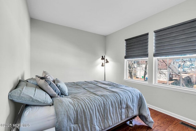 bedroom with visible vents, baseboards, and wood finished floors