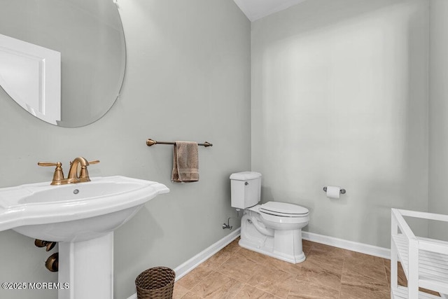 bathroom featuring tile patterned floors, toilet, baseboards, and a sink