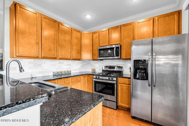 kitchen featuring dark stone countertops, light wood-style flooring, a sink, stainless steel appliances, and tasteful backsplash