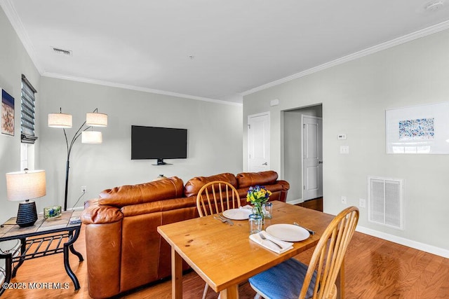 dining space featuring crown molding, light wood-style floors, visible vents, and baseboards